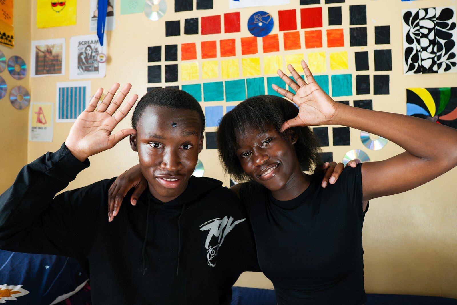 Two young people smiling and making playful hand gestures.
